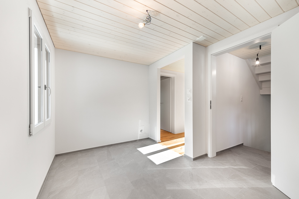 Helles, leerstehendes Zimmer mit Holzdecke und zwei Türen