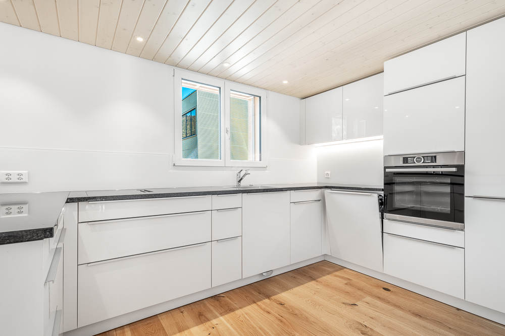 Moderne weiße Küche mit Holzdecke