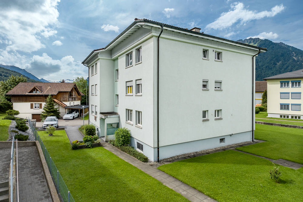 Mehrfamilienhaus mit Garten und Bergkulisse
