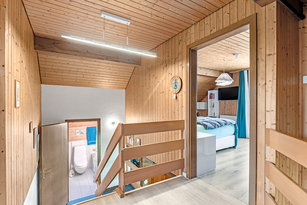 Holzverkleideter Flur mit Treppe und Blick ins Schlafzimmer