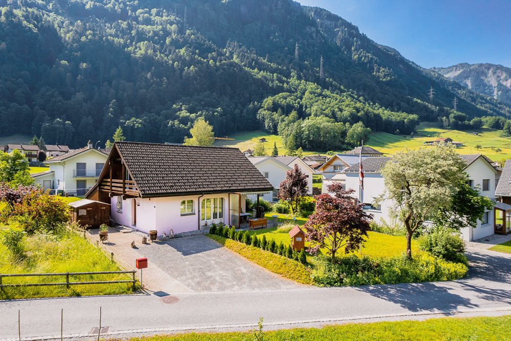 Haus mit Garten vor Bergkulisse