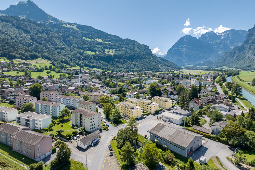 Luftaufnahme eines alpinen Orts mit Bergpanorama