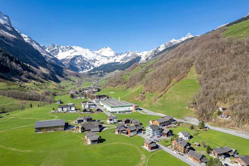 Alpenlandschaft mit Tal, Dorf und schneebedeckten Gipfeln