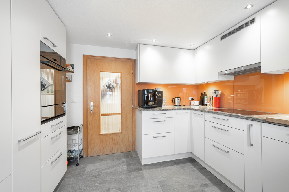 Moderne helle Küche mit orangefarbener Rückwand