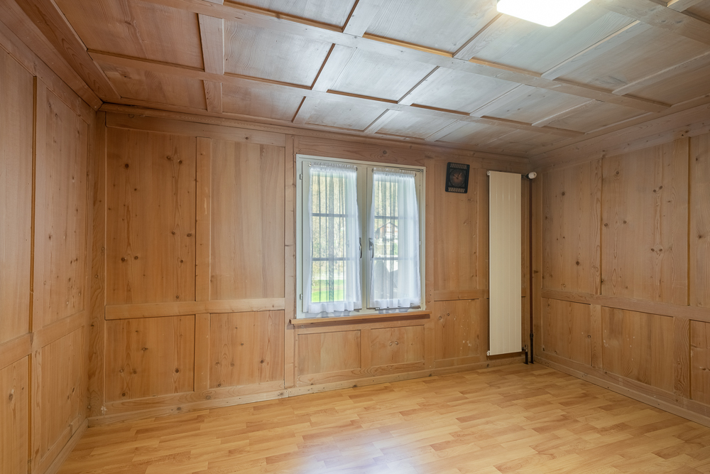 Leerer Holzraum mit Fenster und Heizkörper