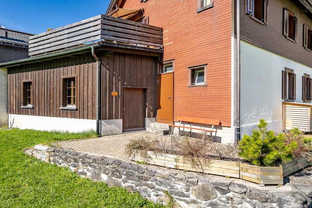 Außenansicht eines Wohngebäudes mit Holzanbau und Terrasse
