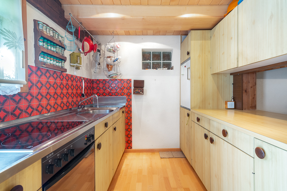 Kleine Küche mit Holzfronten und roter Fliesenrückwand