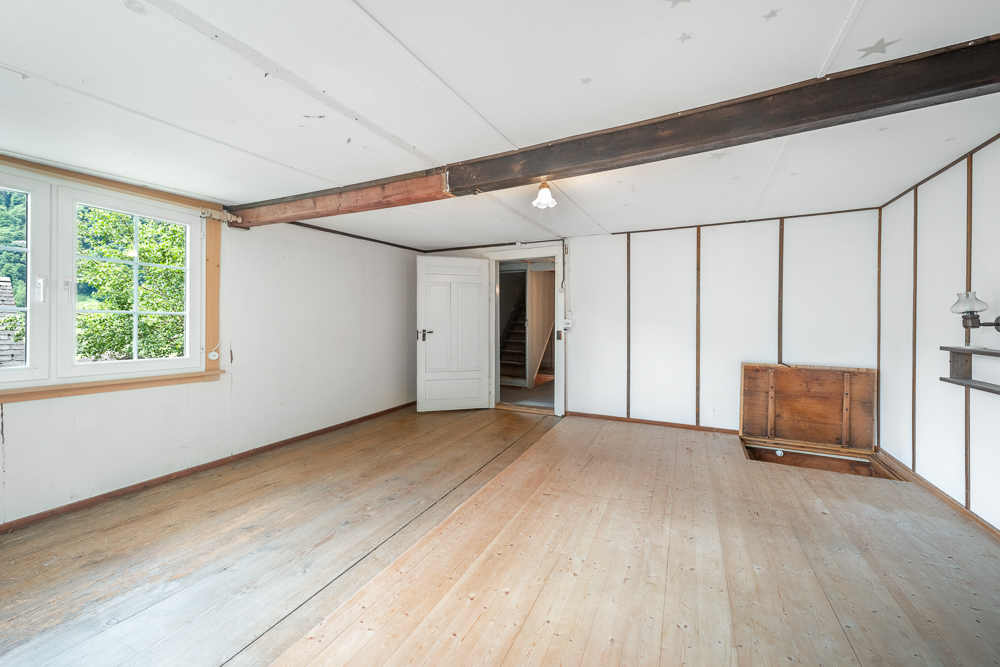 Großer leerer Innenraum mit Holzboden und sichtbaren Balken