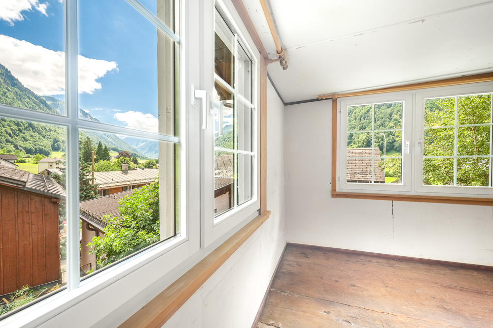 Heller Raum mit großen Fenstern und Bergblick