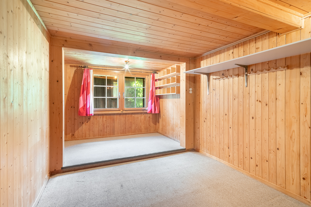Holzvertäfelter Raum mit Fenster und Einbauregalen
