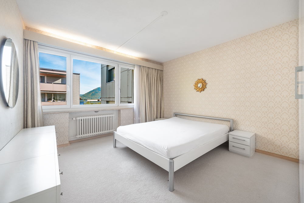 Helles Schlafzimmer mit großem Fenster und Blick nach draußen