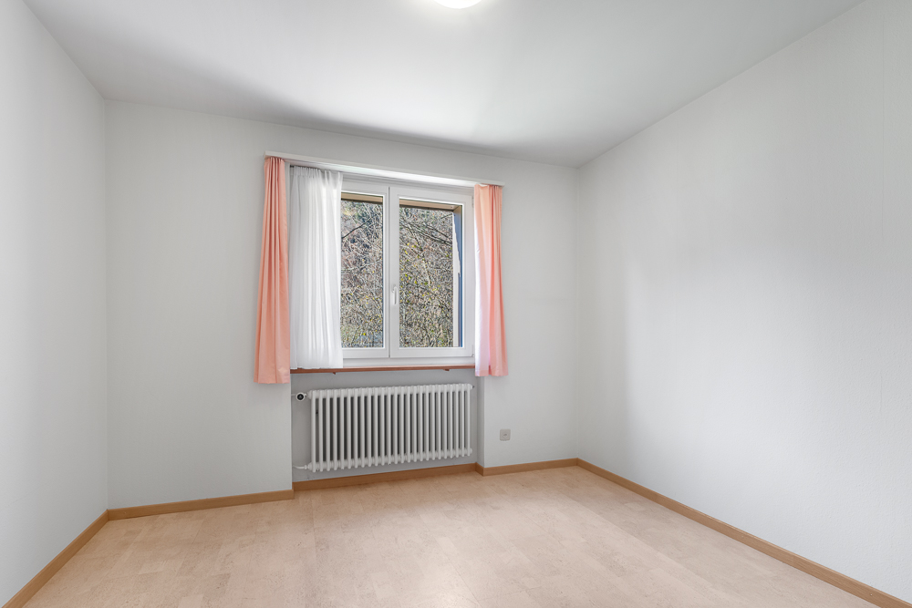 Heller, leerer Raum mit Fenster und Heizkörper
