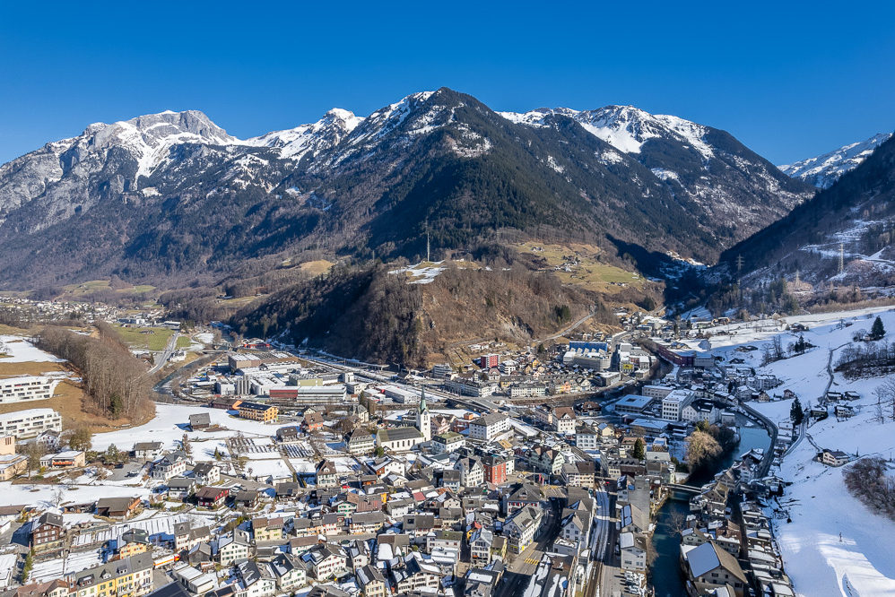 Luftaufnahme einer verschneiten Alpenstadt mit Fluss und Bergen