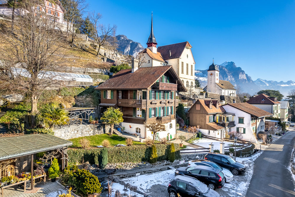 Dorfansicht mit Alpenkulisse und historischen Gebäuden