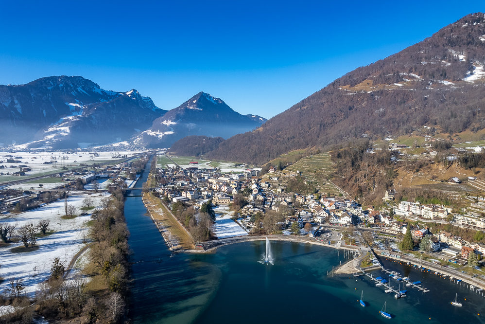 Luftaufnahme einer alpinen Tallandschaft mit See und Ort