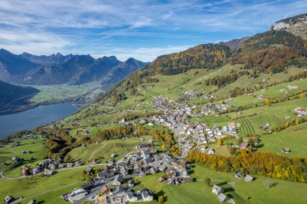 Luftaufnahme eines alpinen Tals mit See und Ortschaft