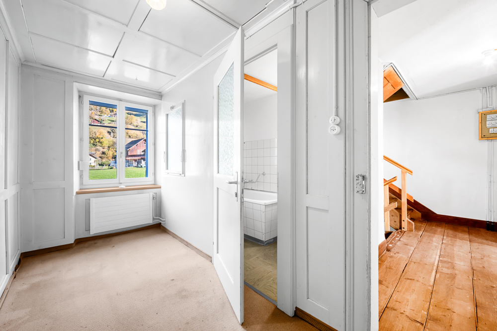 Heller Flur mit Fenster und sichtbarer Treppe