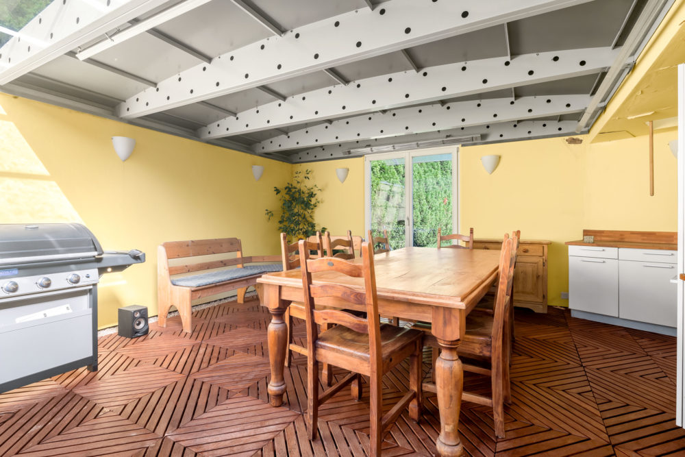 Überdachte Terrasse mit Esstisch und Grill