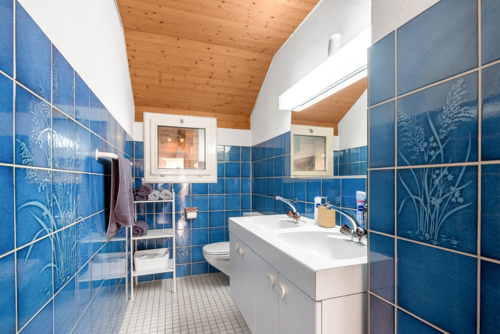 Badezimmer mit blauen Wandfliesen und Holzdecke