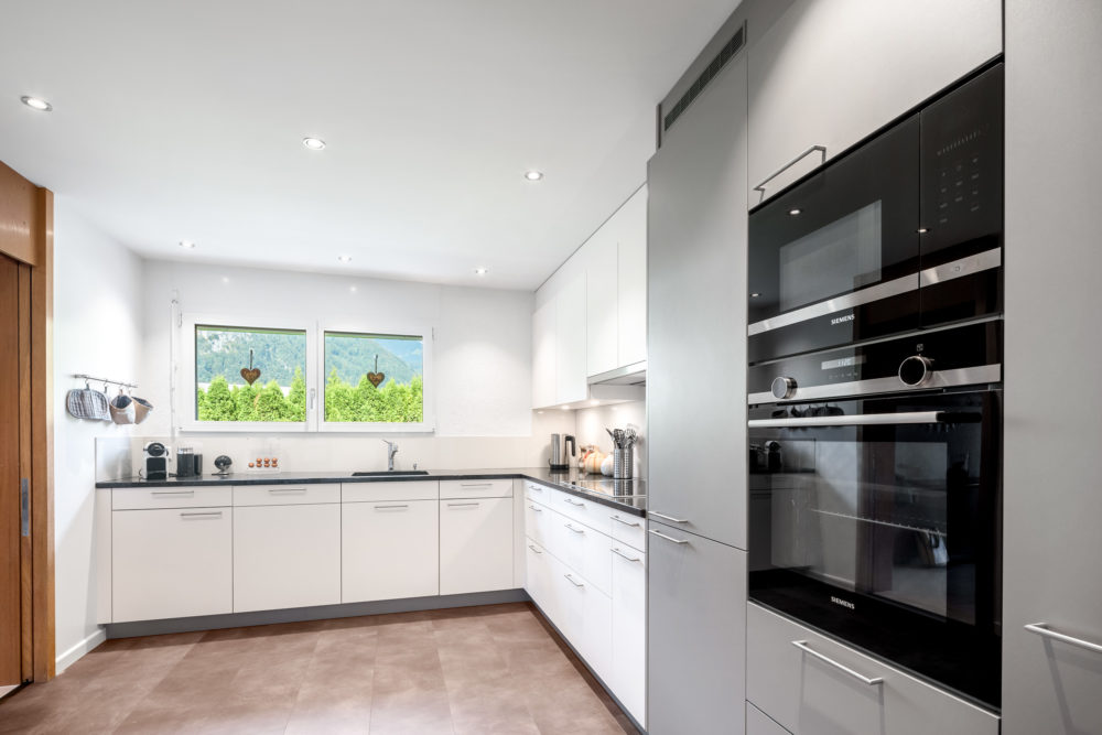 Moderne weiße Einbauküche mit Fensterblick