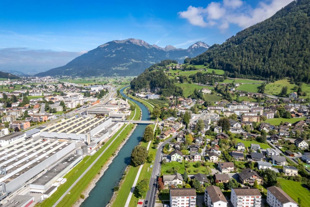 Luftaufnahme einer alpinen Stadt mit Fluss und Bergen