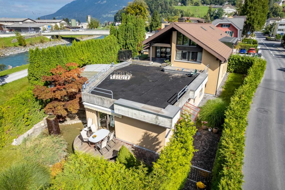 Luftaufnahme eines Einfamilienhauses mit Dachterrasse am Fluss