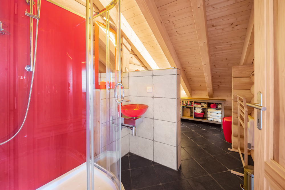 Dachgeschoss-Badezimmer mit Holzverkleidung und farbigen Akzenten