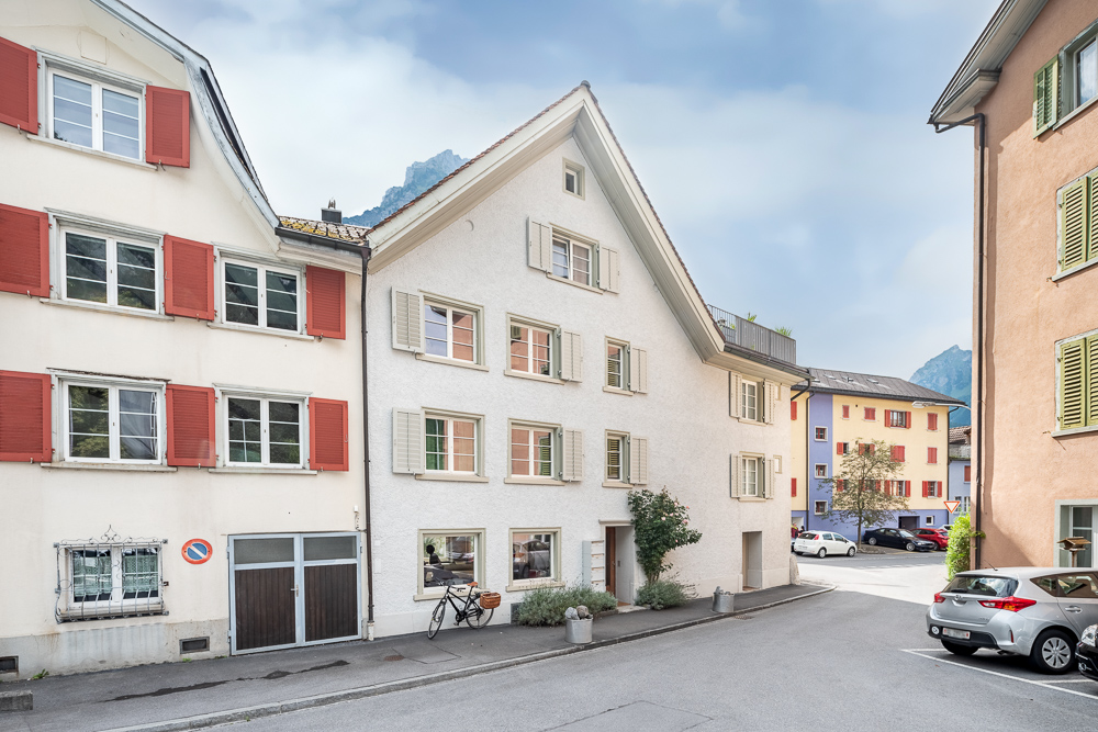 Straßenansicht mit Wohnhäusern in alpiner Umgebung