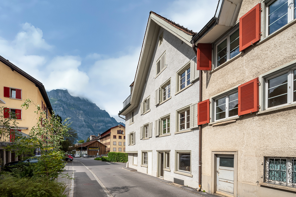 Straßenszene mit alpinem Hintergrund und Wohnhäusern