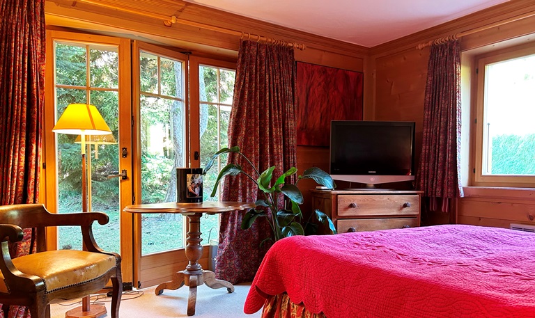 Gemütliches Schlafzimmer mit Holzvertäfelung und Balkonzugang