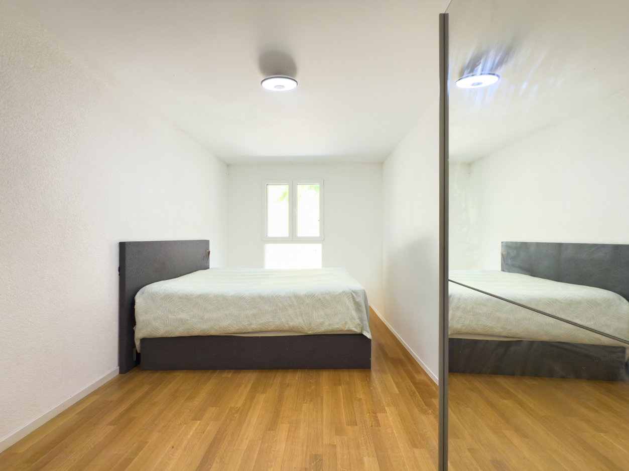 Helles Schlafzimmer mit Bett und Spiegelschrank