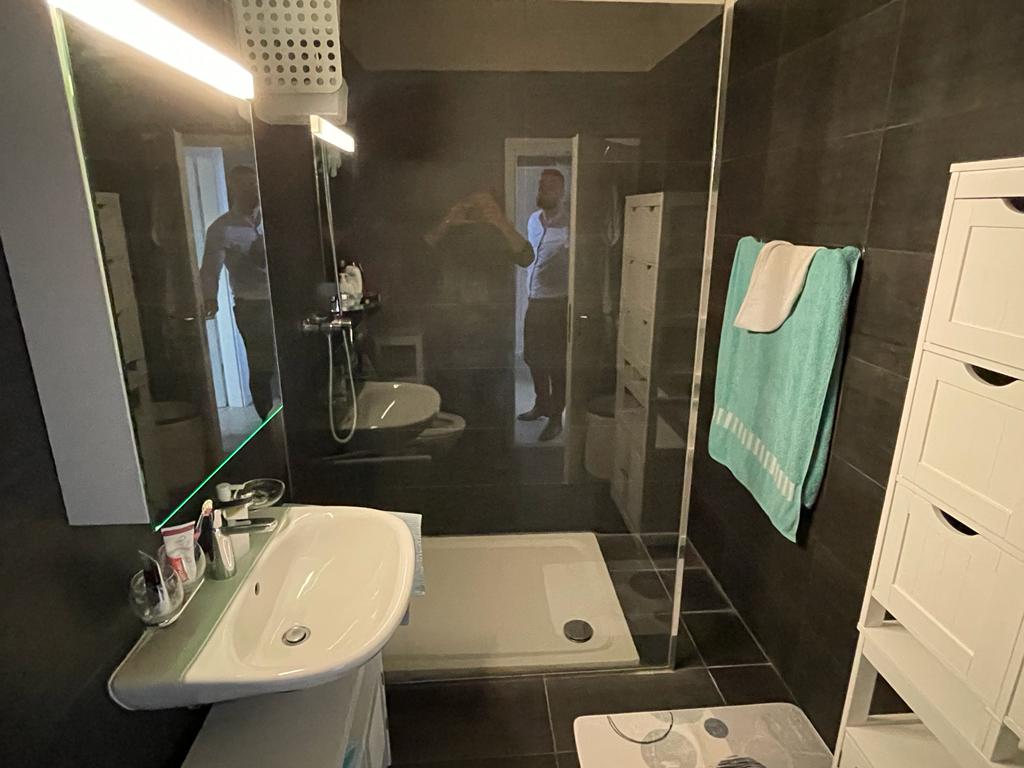 Modernes Badezimmer mit dunkler Wandverkleidung und Glasdusche