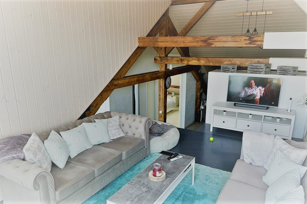 Dachgeschoss-Wohnzimmer mit sichtbaren Holzbalken