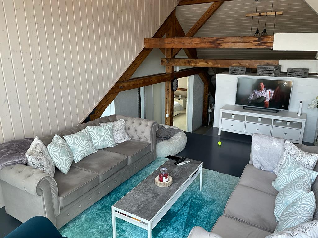 Dachgeschoss-Wohnzimmer mit sichtbaren Holzbalken