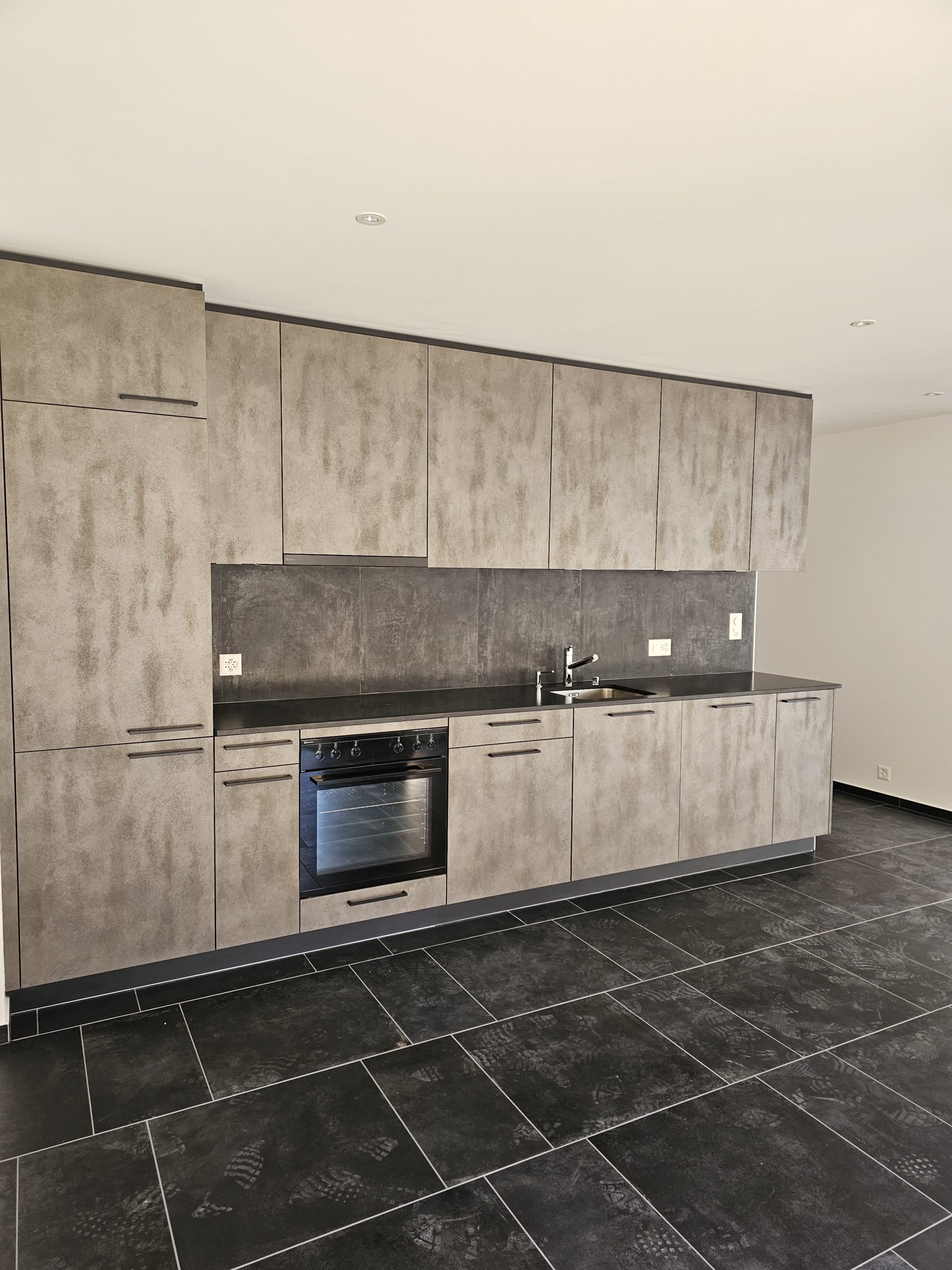 Moderne Küche mit dunklem Boden und Betonoptik