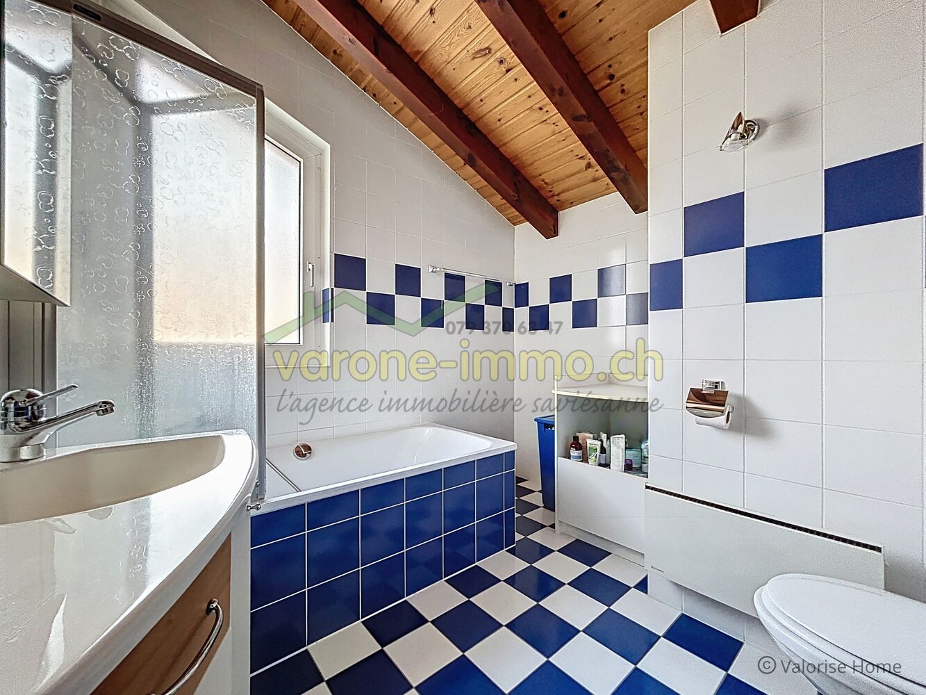 Badezimmer mit blau-weißem Fliesenmuster und Holzbalkendecke