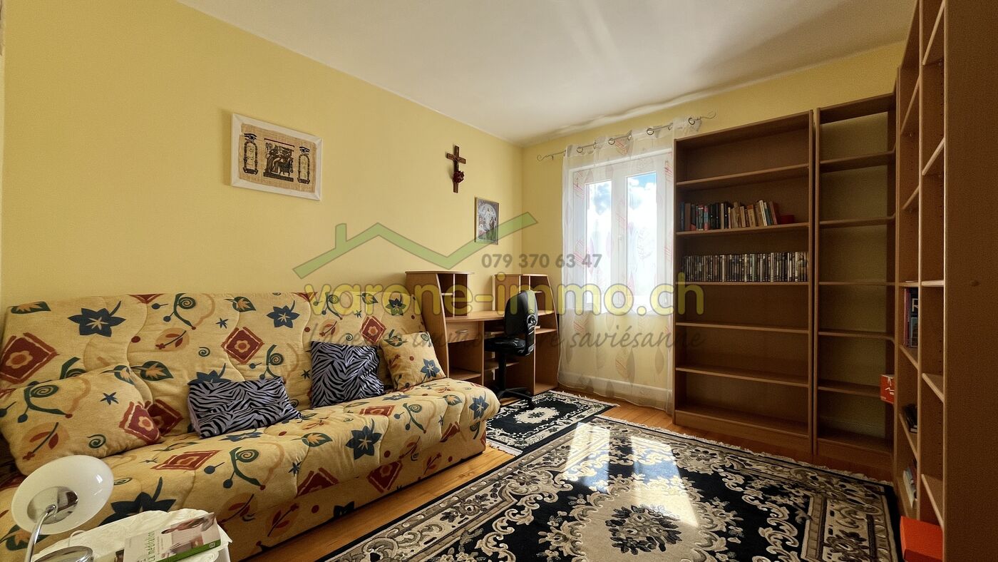 Wohnzimmer mit Sofa, Schreibtisch und Regalen