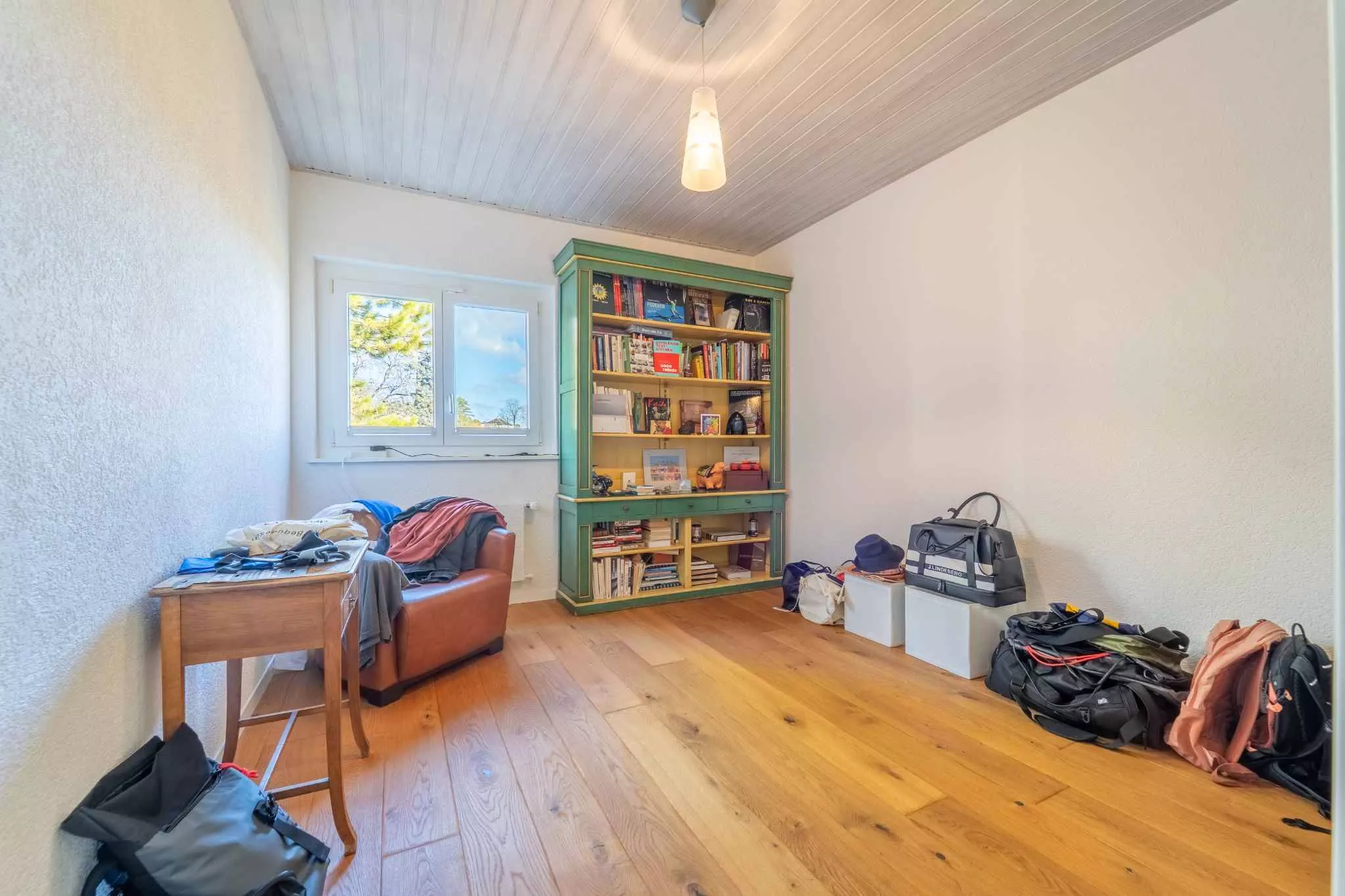 Helles Zimmer mit Holzboden und Bücherregal