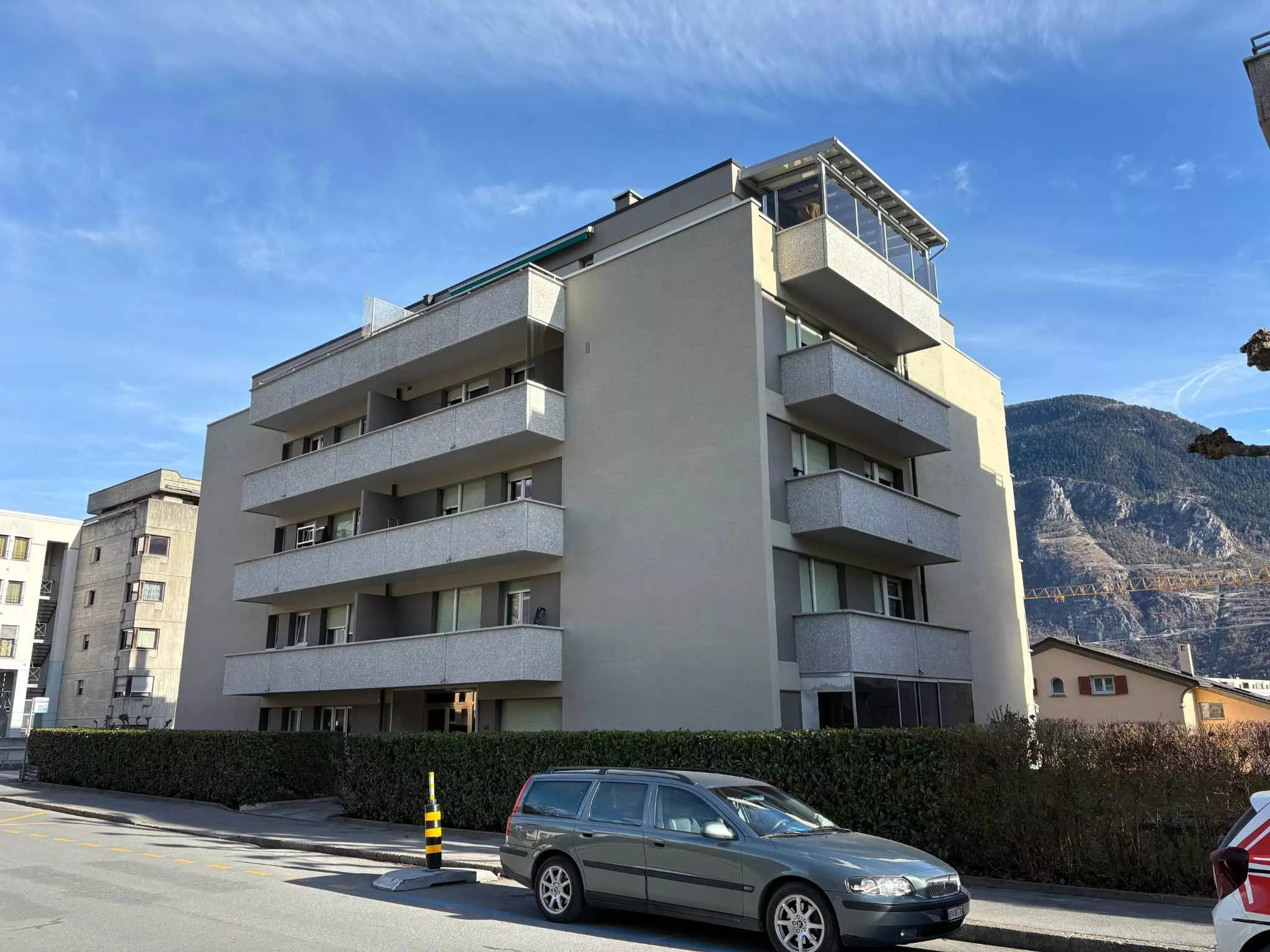 Mehrfamilienhaus mit Balkonen vor Bergkulisse