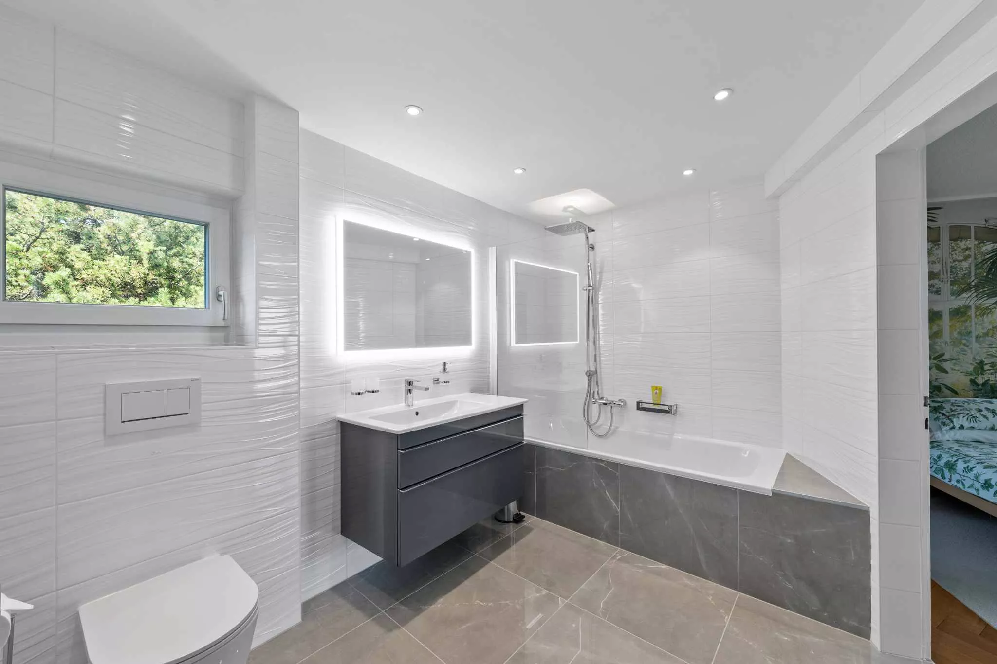 Modernes Badezimmer mit Badewanne und beleuchtetem Spiegel