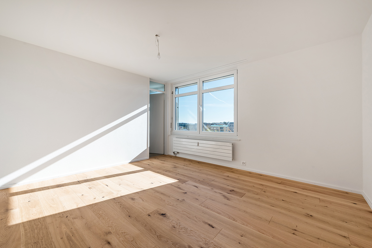 Heller leerer Wohnraum mit Holzboden und Fenster