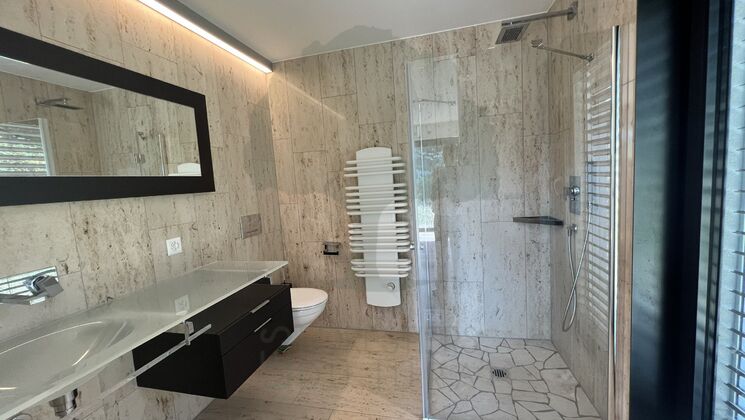 Luxuriöses Badezimmer mit Natursteinoptik und Glasdusche