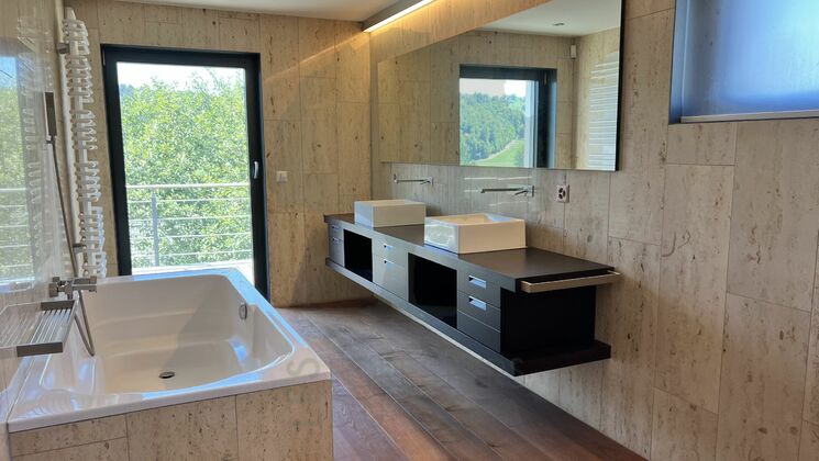 Modernes Badezimmer mit Natursteinoptik und freistehender Badewanne