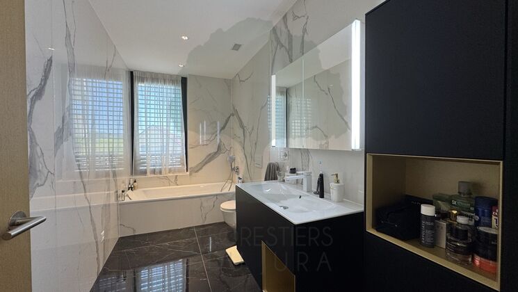 Luxuriöses Badezimmer mit Badewanne und dunklem Waschtisch