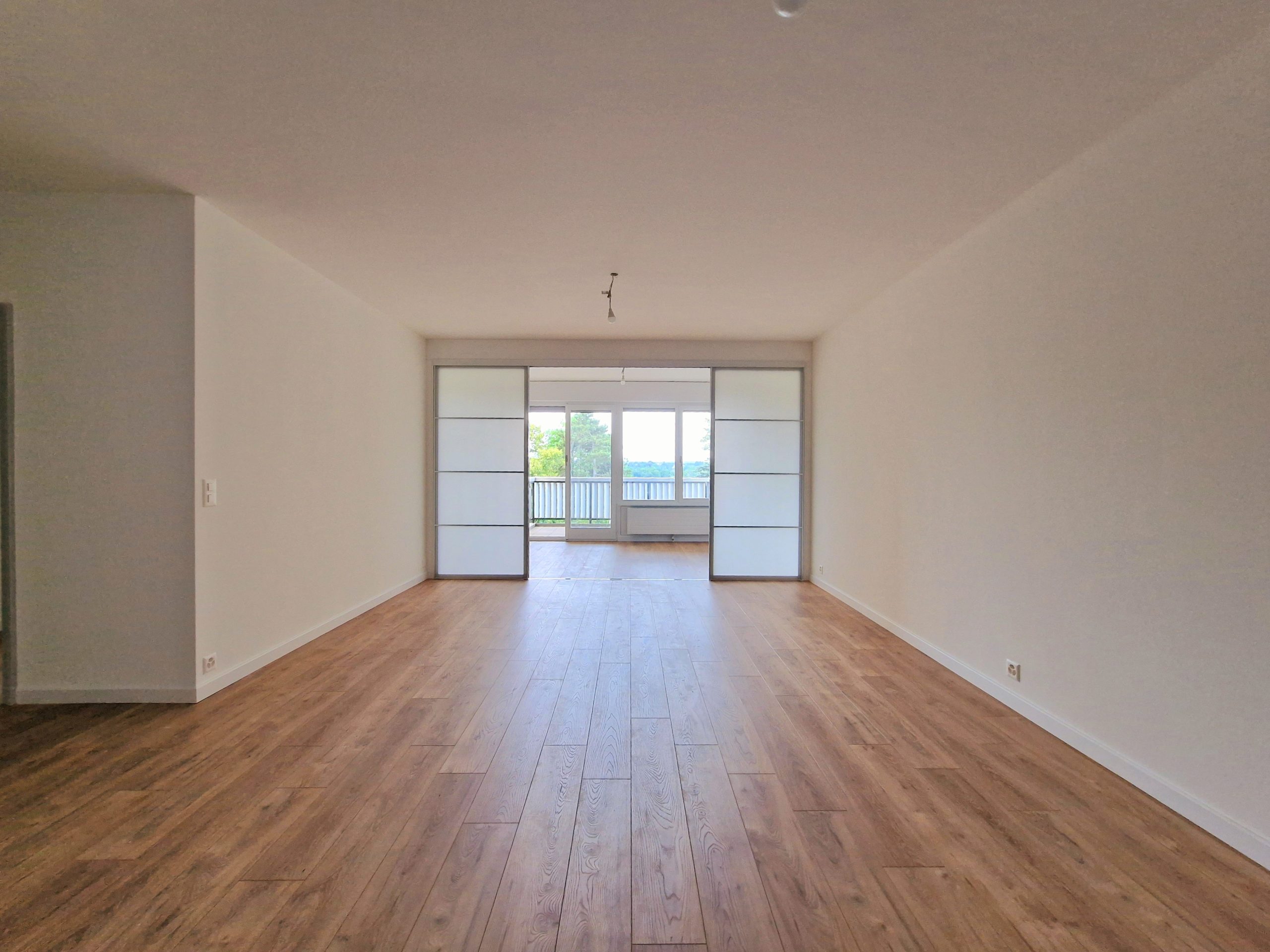 Leerer, heller Wohnraum mit Schiebetür zur Terrasse