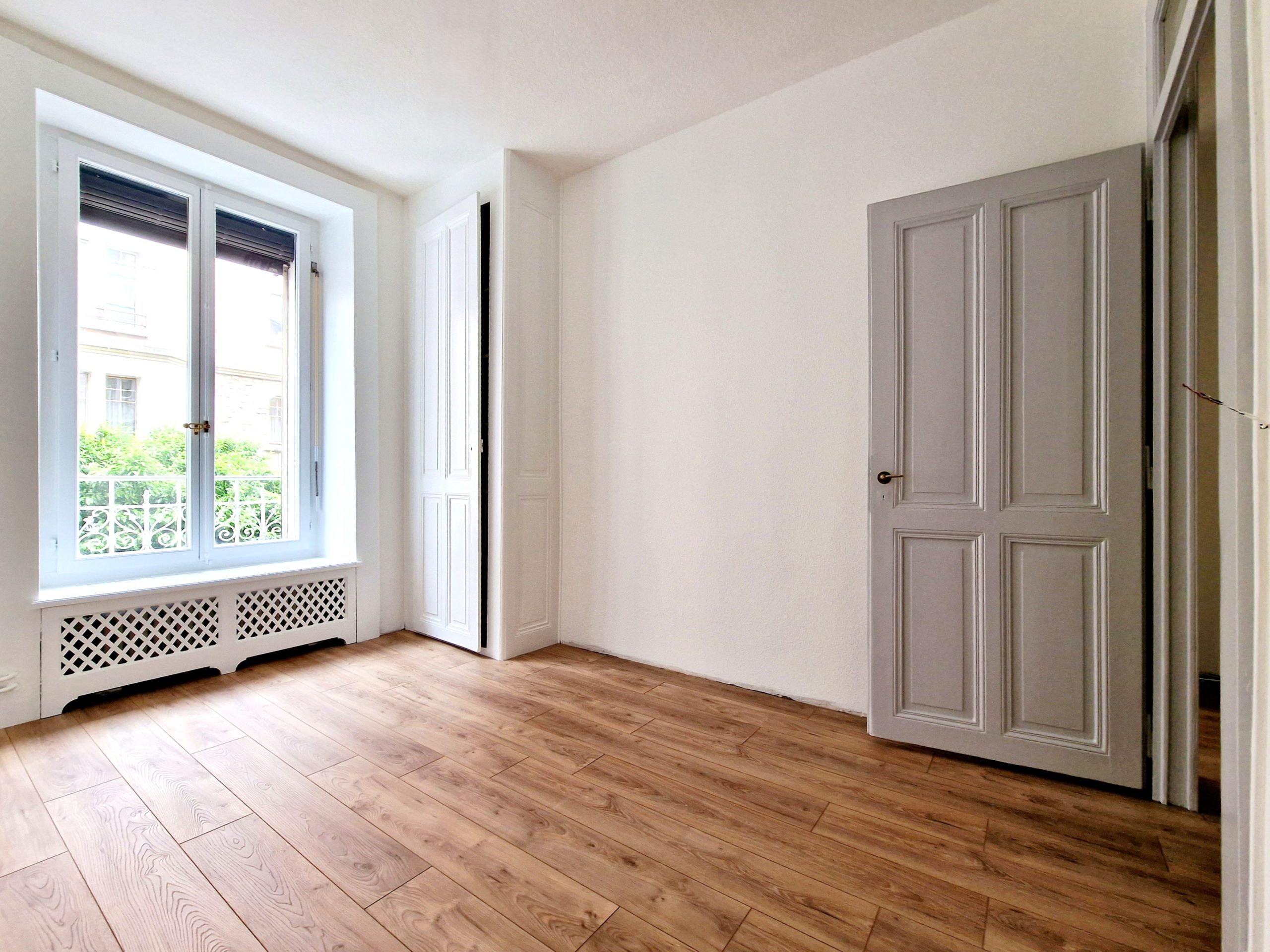 Helles, leeres Zimmer mit Dielenboden und Fenstern