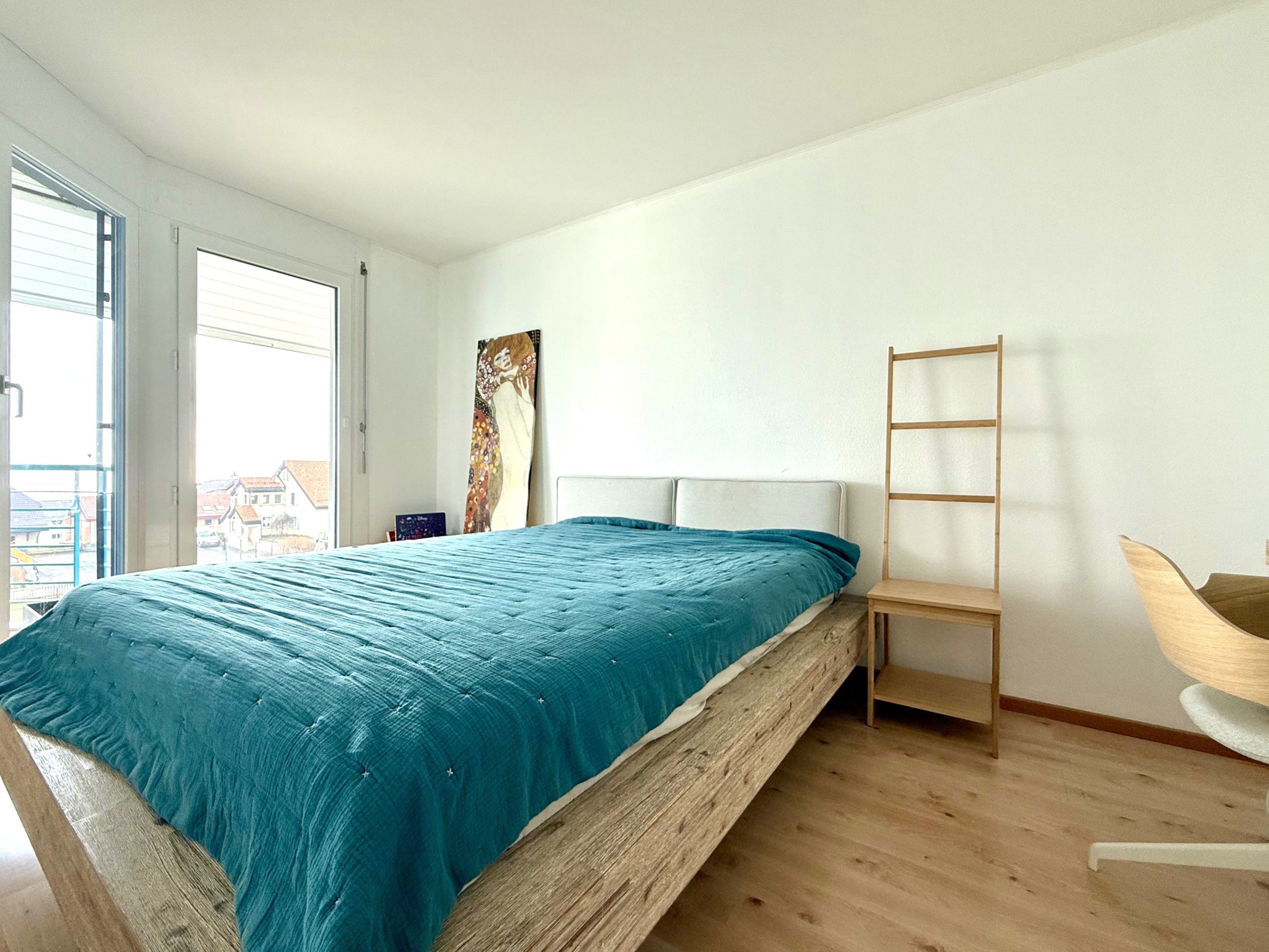 Helles Schlafzimmer mit Bett und Balkonfenstern