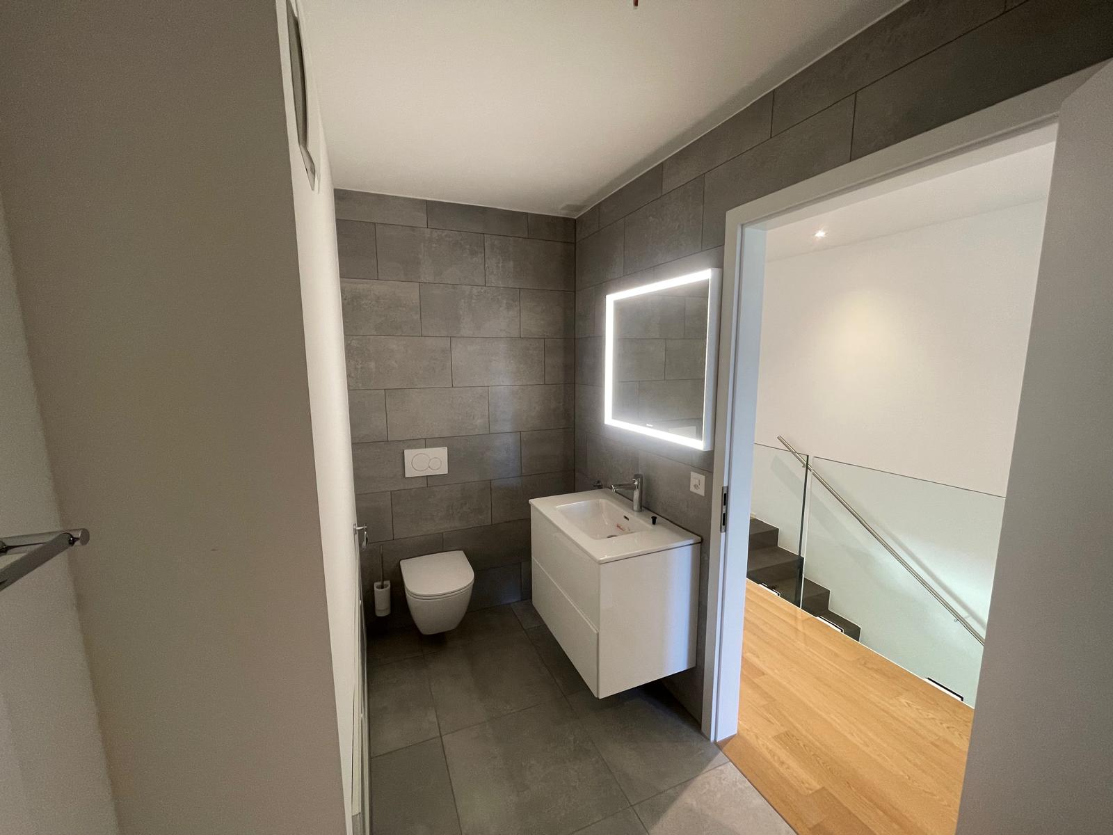 Modernes Gäste-WC mit beleuchtetem Spiegel