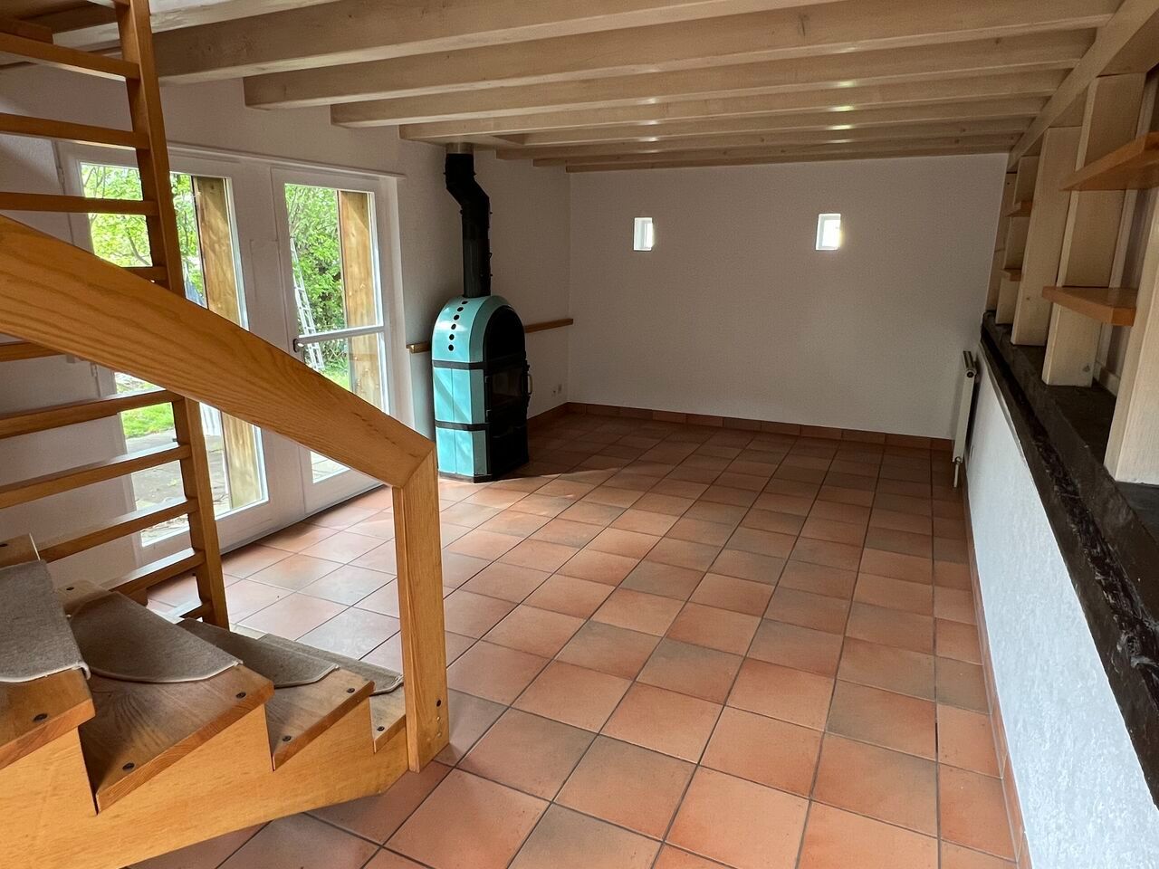 Wohnraum mit Holztreppe und Ofen