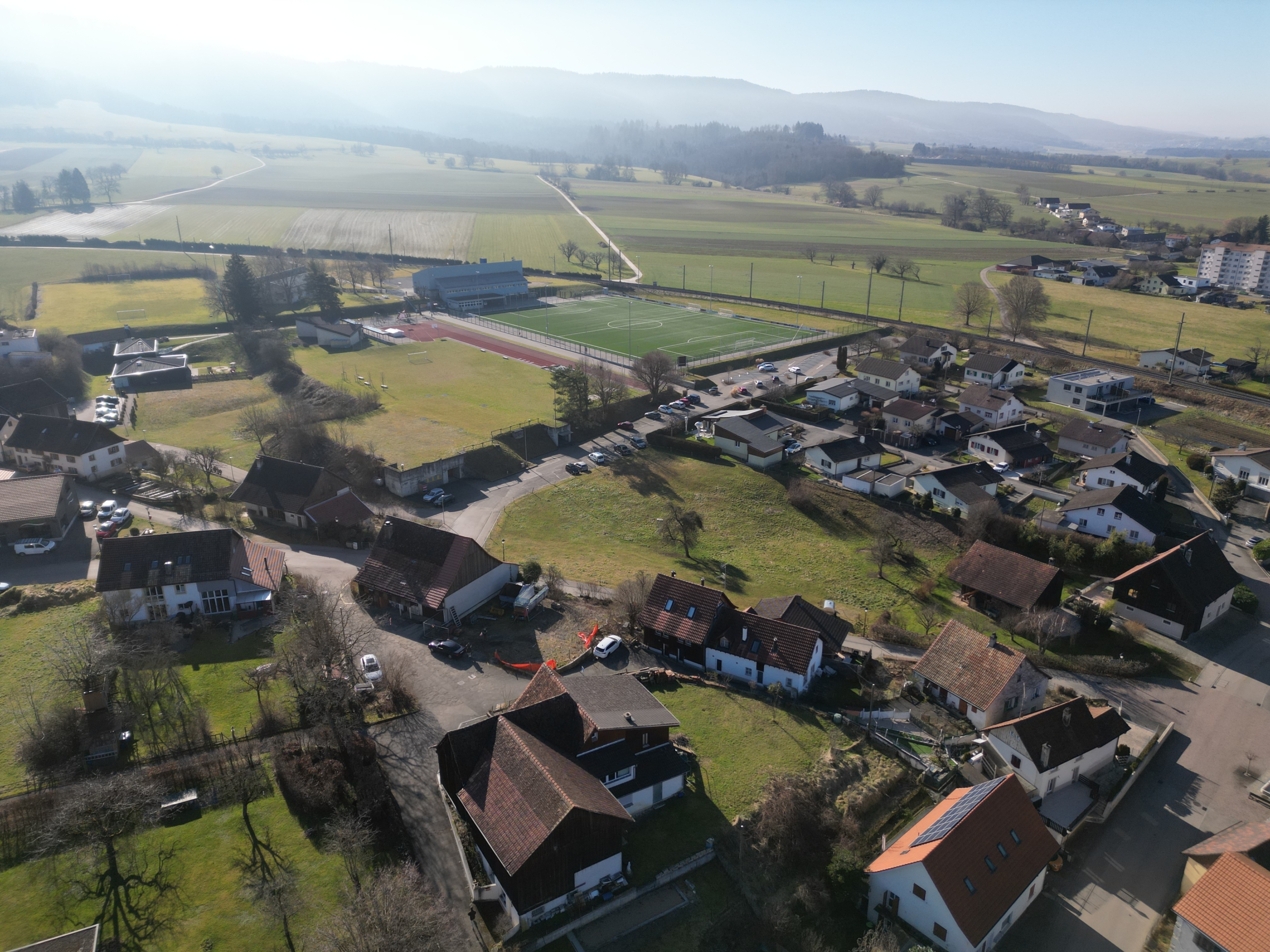 Luftaufnahme eines ländlichen Wohngebiets mit Sportanlage
